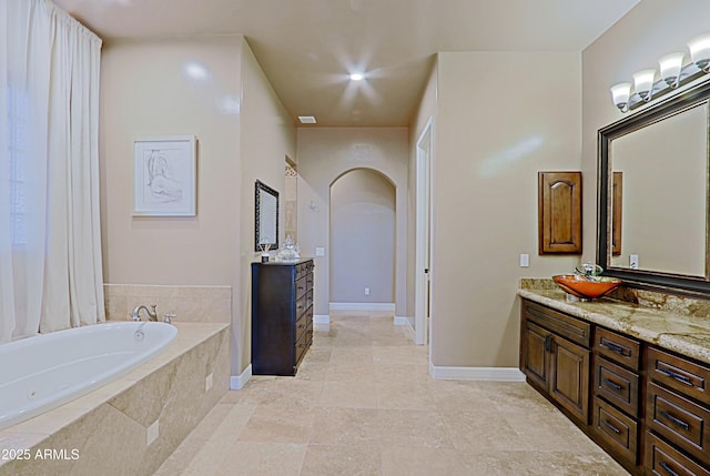 bathroom featuring visible vents, tile patterned floors, baseboards, a bath, and vanity