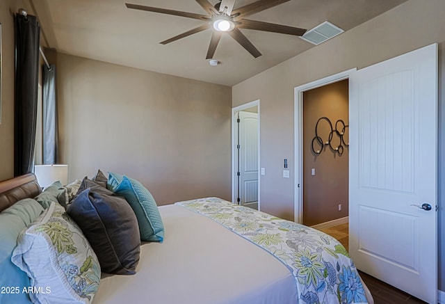 bedroom featuring ceiling fan, visible vents, baseboards, and wood finished floors