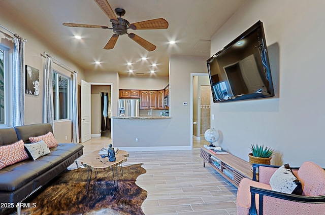 living room featuring recessed lighting, a ceiling fan, light wood-style floors, and baseboards