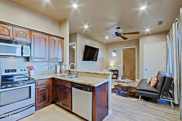 kitchen with light stone countertops, visible vents, a peninsula, a sink, and appliances with stainless steel finishes