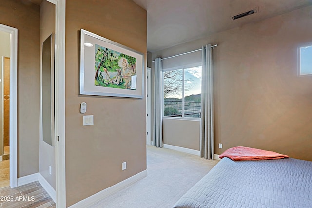 bedroom with visible vents, baseboards, and light colored carpet