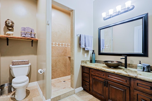 bathroom featuring vanity, baseboards, tiled shower, tile patterned flooring, and toilet