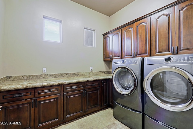 laundry area featuring separate washer and dryer, cabinet space, and light floors