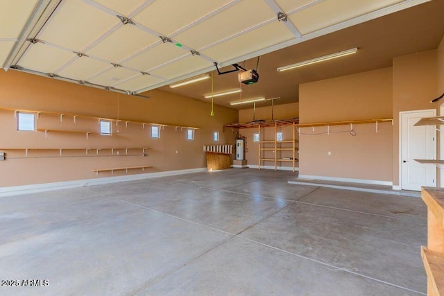 garage featuring baseboards, a garage door opener, and water heater