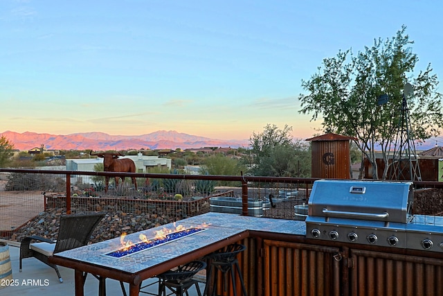 view of patio with a mountain view, area for grilling, and an outdoor fire pit