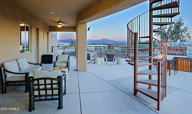 view of patio / terrace featuring outdoor lounge area, stairway, a mountain view, and ceiling fan