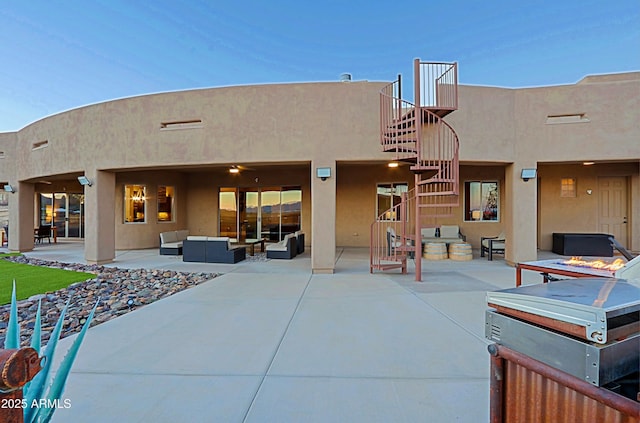 rear view of property featuring stucco siding, an outdoor hangout area, a patio, and stairway