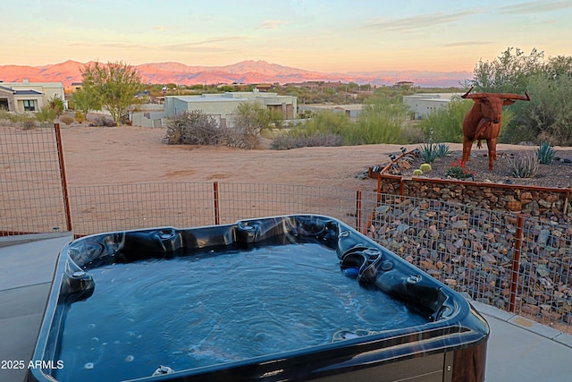 exterior space featuring a mountain view, fence, and a hot tub