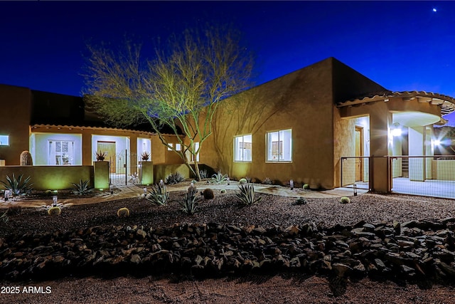 view of front of house featuring stucco siding and fence