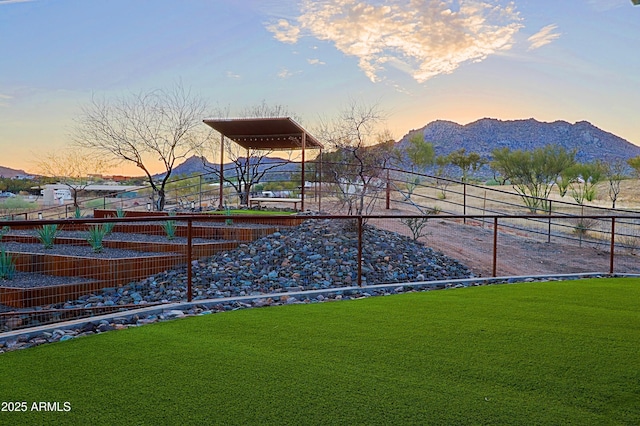 yard at dusk with a mountain view and fence