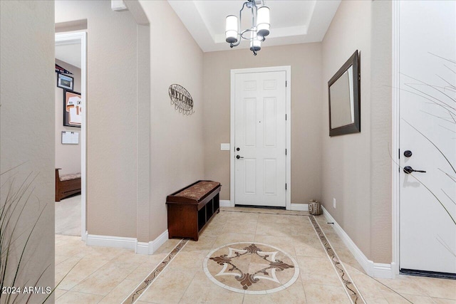 tiled foyer with a tray ceiling and a chandelier