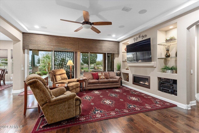 living room featuring dark wood-type flooring, built in features, and ceiling fan