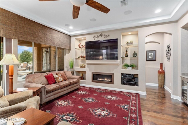 living room featuring hardwood / wood-style flooring, built in features, and ceiling fan