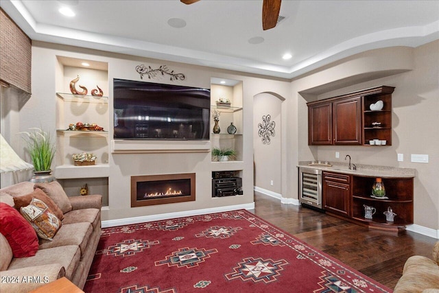 living room with wine cooler, built in shelves, dark hardwood / wood-style flooring, and indoor bar