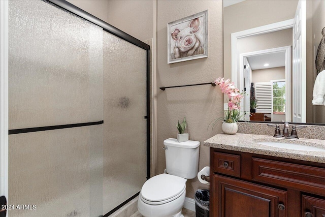 bathroom featuring vanity, a shower with door, and toilet