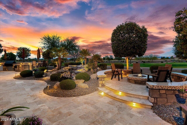 patio terrace at dusk with area for grilling and a fire pit