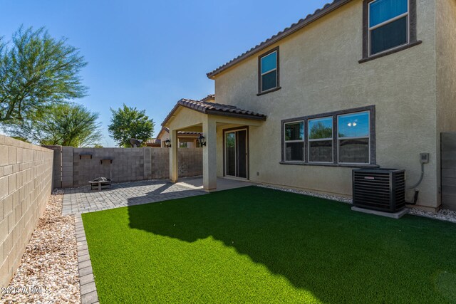 rear view of house with a patio, a fire pit, a lawn, and central air condition unit