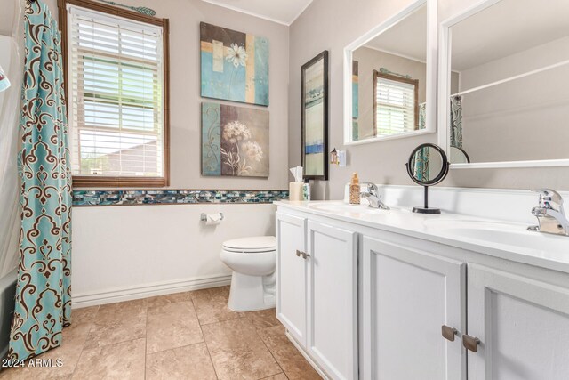 bathroom featuring tile patterned floors, a wealth of natural light, vanity, and toilet