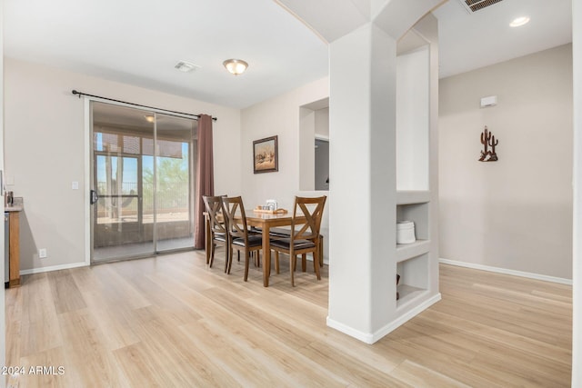 dining space featuring built in shelves and light hardwood / wood-style flooring