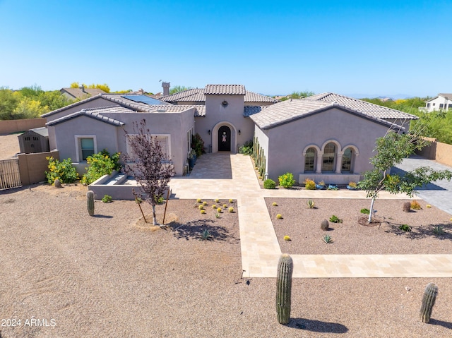 mediterranean / spanish house featuring a tile roof, fence, and stucco siding