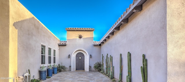 view of exterior entry featuring a tile roof and stucco siding