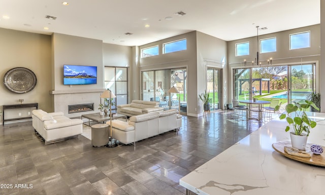 living area featuring visible vents, a premium fireplace, and a towering ceiling