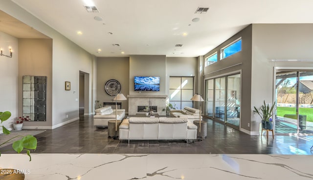 living room with visible vents, a wealth of natural light, and a glass covered fireplace