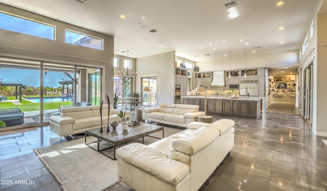 living area featuring a towering ceiling, visible vents, and recessed lighting