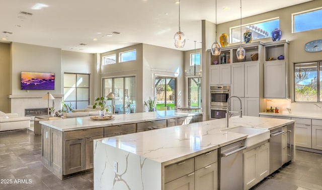 kitchen featuring a spacious island, a glass covered fireplace, open floor plan, and a sink