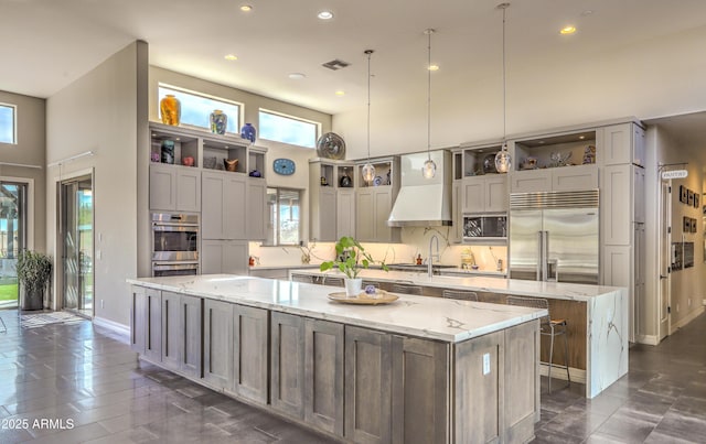 kitchen featuring a large island, a high ceiling, open shelves, and built in appliances