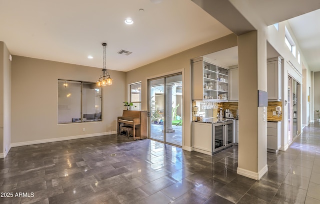 interior space with wine cooler, a notable chandelier, recessed lighting, visible vents, and baseboards