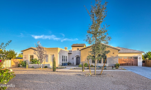 mediterranean / spanish home featuring a garage, a gate, driveway, and stucco siding