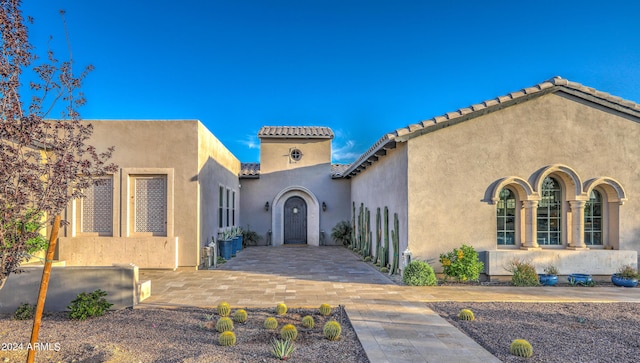 exterior space with a tiled roof and stucco siding