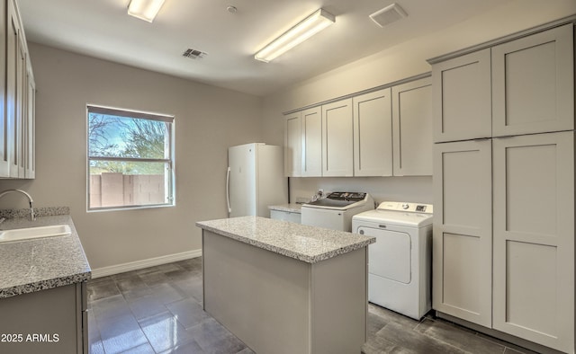 laundry area featuring cabinet space, visible vents, a sink, and washing machine and clothes dryer