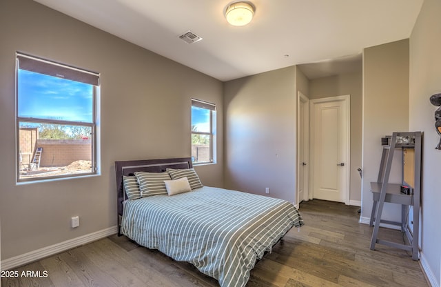 bedroom with wood finished floors, visible vents, and baseboards