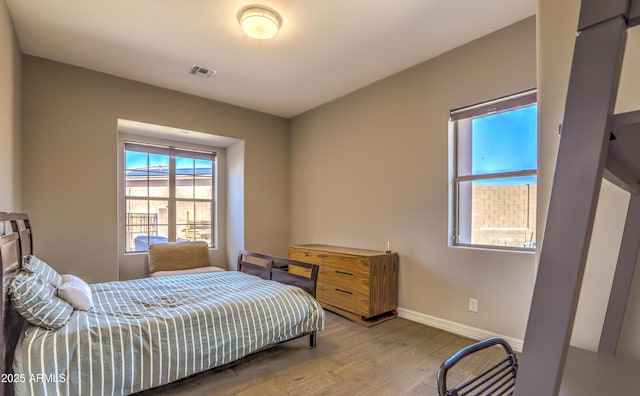 bedroom featuring visible vents, baseboards, and wood finished floors