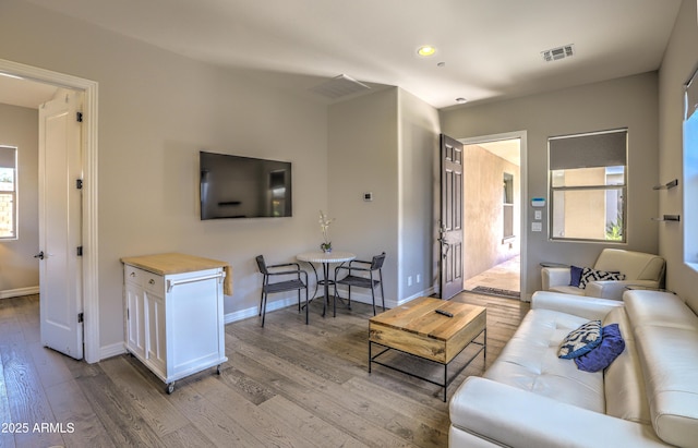 living area with recessed lighting, light wood-type flooring, visible vents, and baseboards