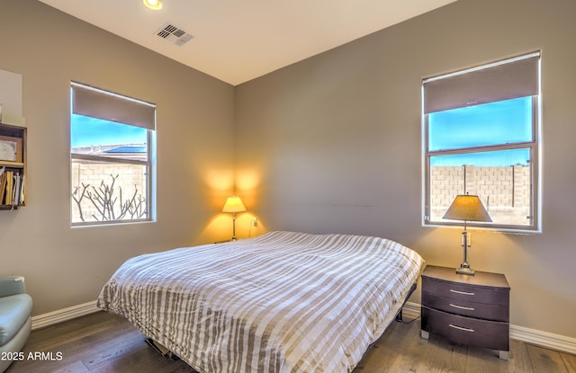 bedroom featuring visible vents, baseboards, and wood finished floors