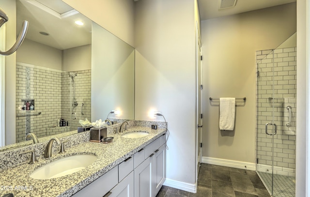 bathroom featuring double vanity, a stall shower, a sink, and baseboards