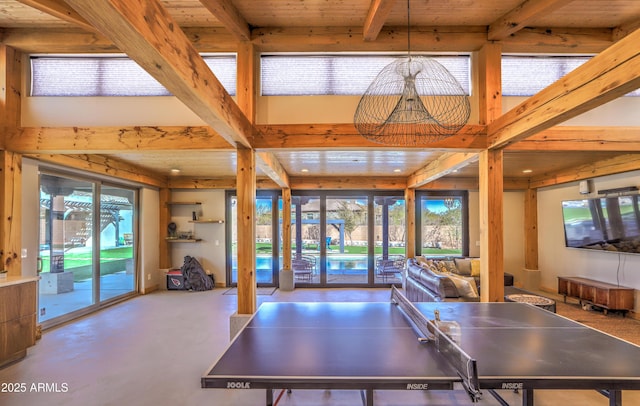 rec room featuring a healthy amount of sunlight, concrete flooring, and beam ceiling