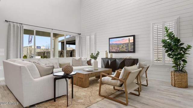 living room featuring a towering ceiling and light hardwood / wood-style flooring