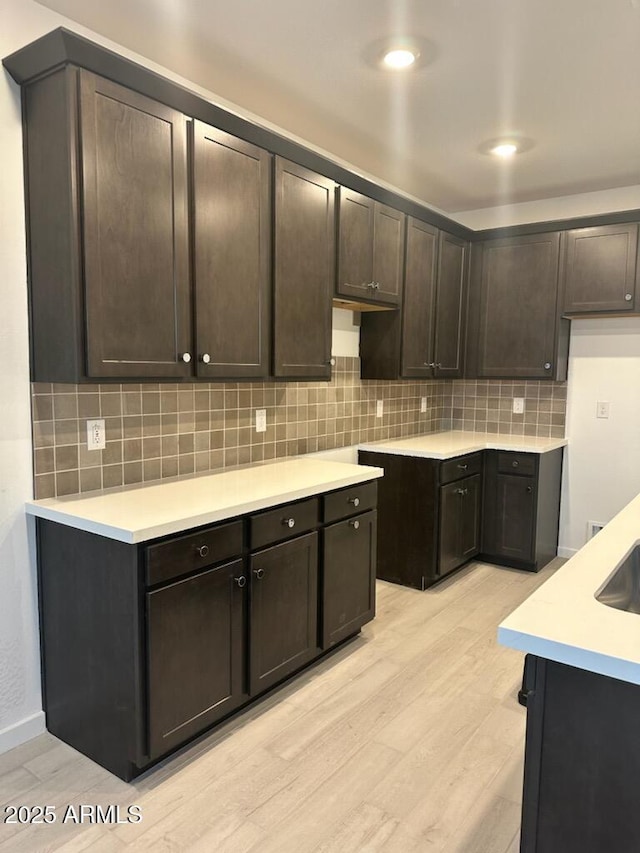 kitchen featuring tasteful backsplash, light wood-type flooring, and dark brown cabinets