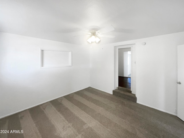 empty room with ceiling fan and dark carpet