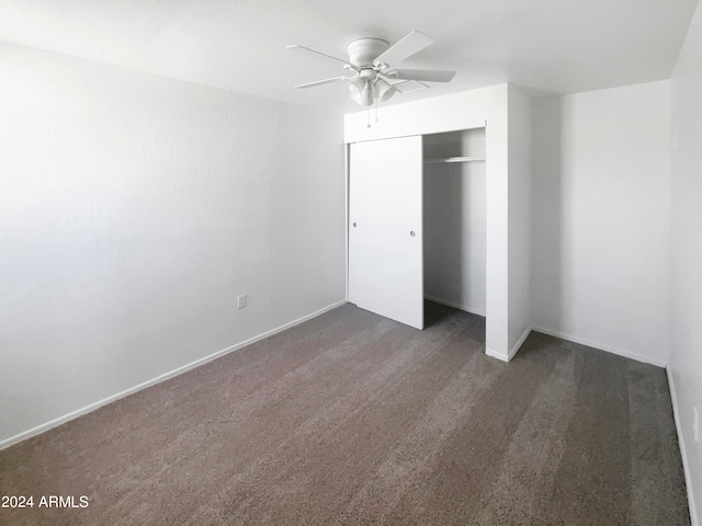 unfurnished bedroom with dark colored carpet, ceiling fan, and a closet