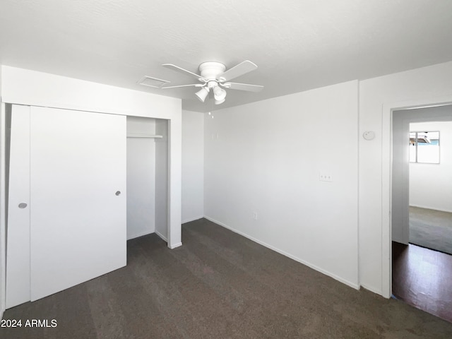 unfurnished bedroom with ceiling fan, a closet, and dark colored carpet