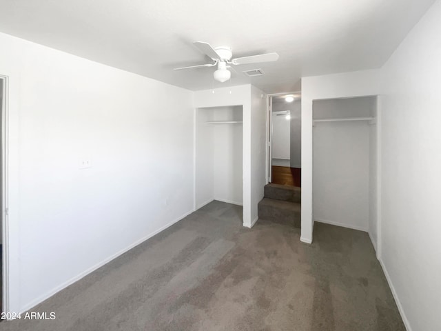 unfurnished bedroom featuring carpet flooring, ceiling fan, and multiple closets