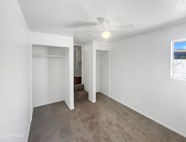 unfurnished bedroom featuring ceiling fan, two closets, and carpet floors