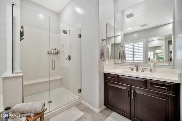 bathroom with walk in shower, vanity, and tile patterned flooring