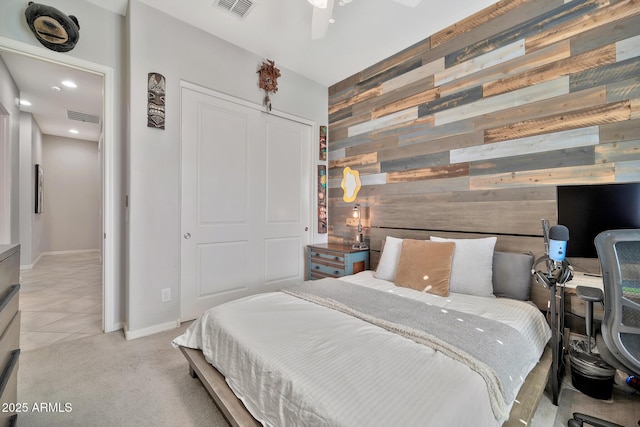 bedroom featuring a closet, light colored carpet, ceiling fan, and wood walls