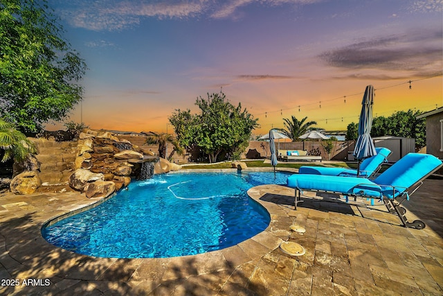 pool at dusk featuring a storage unit, pool water feature, and a patio area